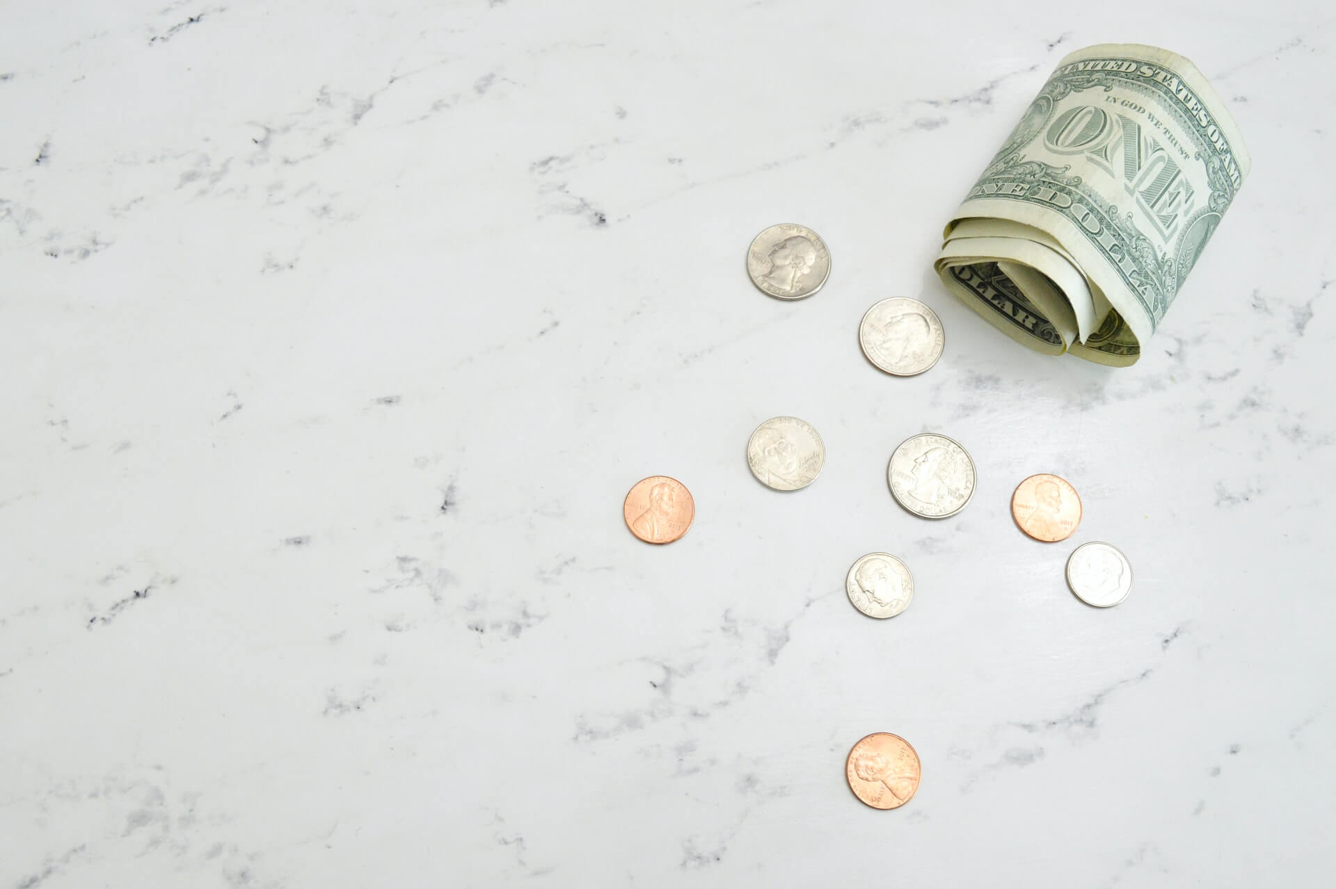 Image of coins and a dollar bill on marble