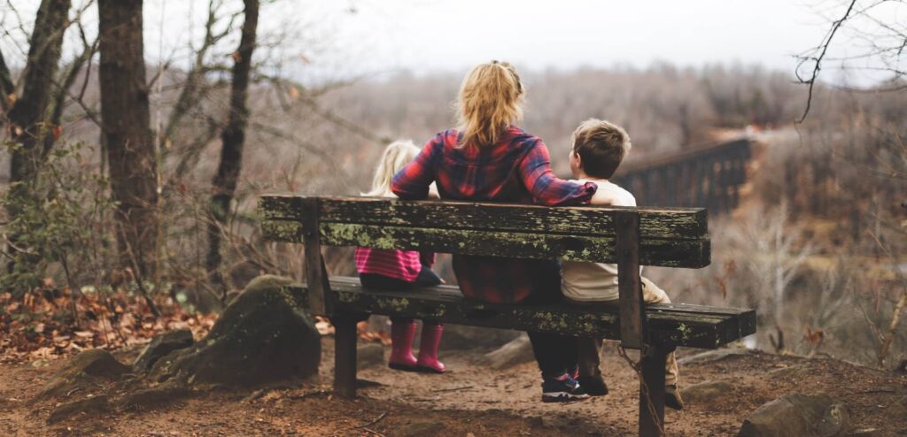 Image of mom on bench with her two kids in a park