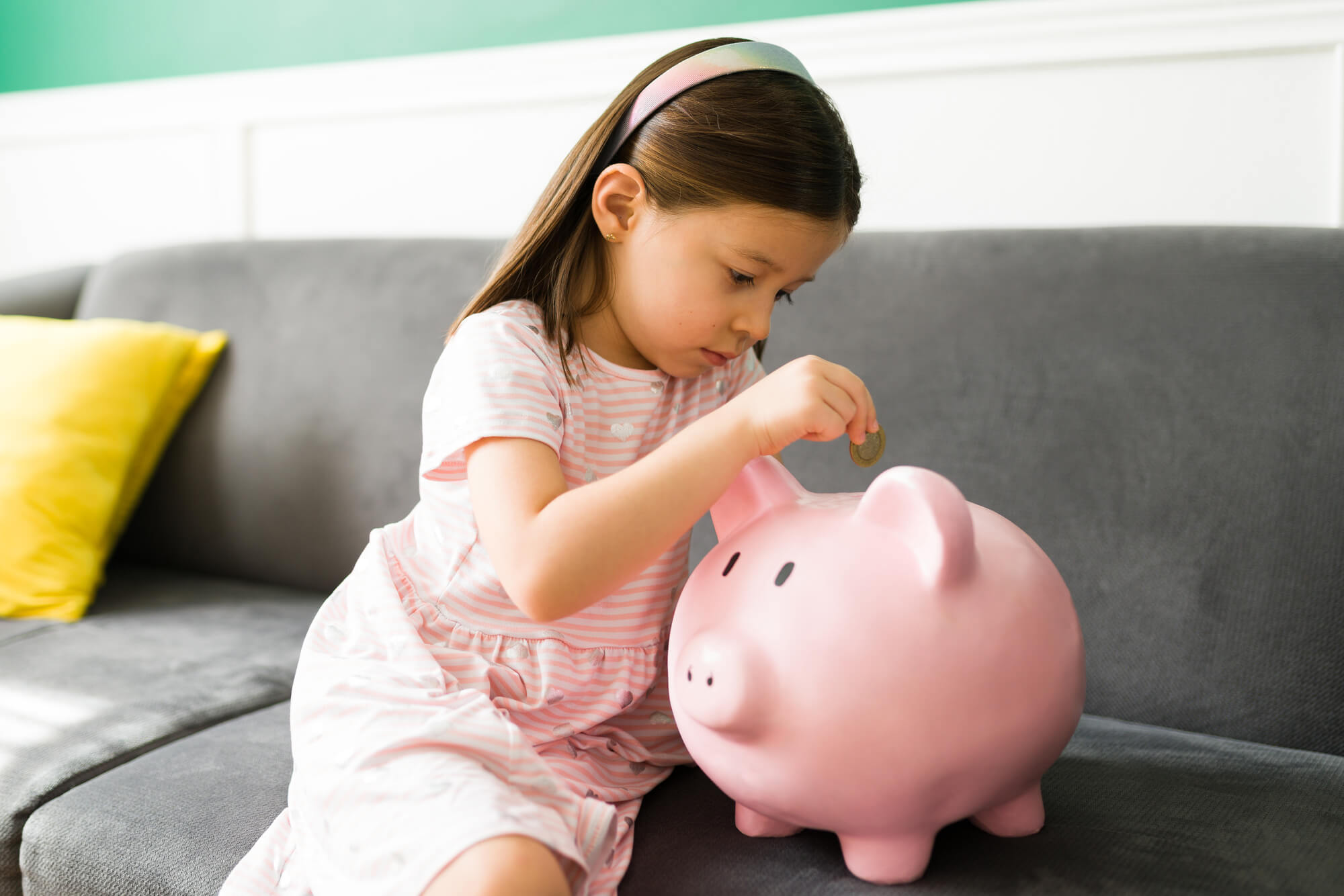 Small child learning how to save money with a piggy bank
